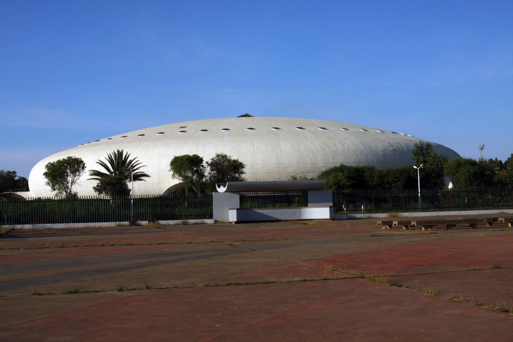 A grey dome of a large building with some trees in the foreground