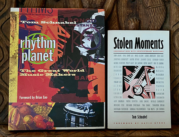 Two books laying face-up on a wooden table. The book on the left has a colorful cover, the book on the right is mostly white with an illustration of musical instruments in the middle.