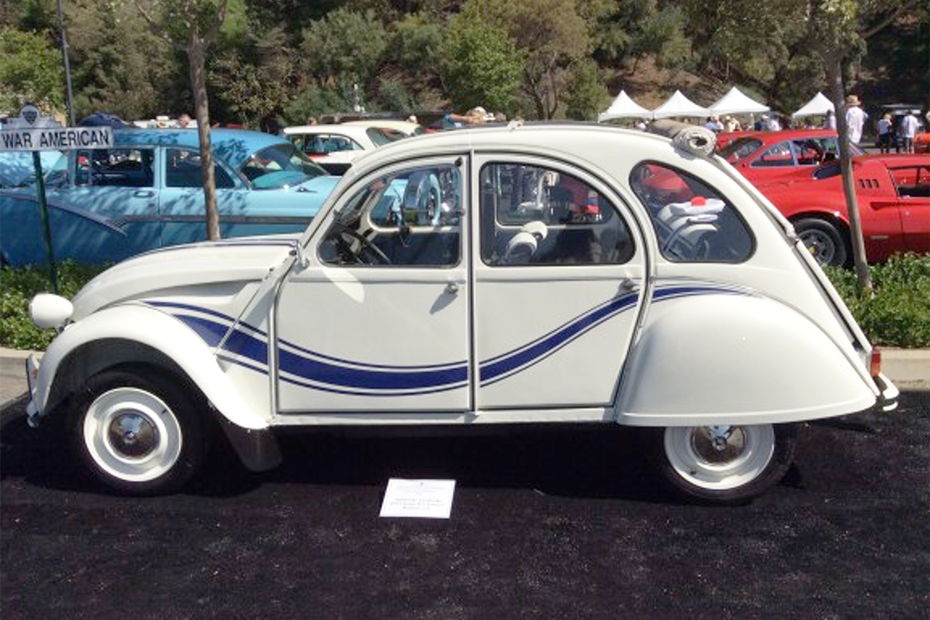 Profile view of a well maintained but old white car with a blue wavy stripe