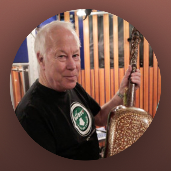 Brown and red borders around a circular photo of an older man holding a musical instrument—possibly a Moroccan Guembri—and smiling. He is wearing a black t-shirt.